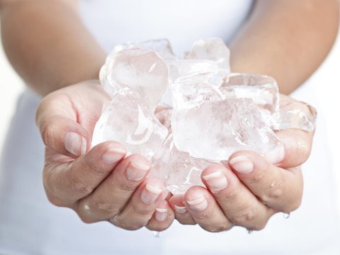 Ice cold hands. Woman hands holding ice cubes - closeup.