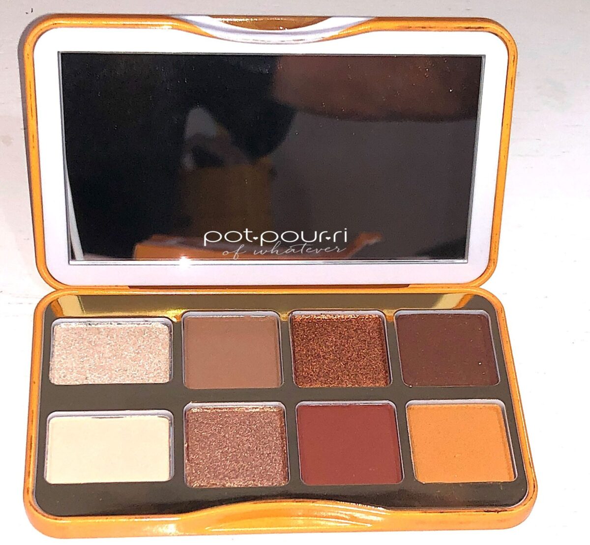 THE HOT BUTTERED RUM PALETTE HAS A MIRROR AND EIGHT EYESHADOWS INSIDE THE COMPACT
